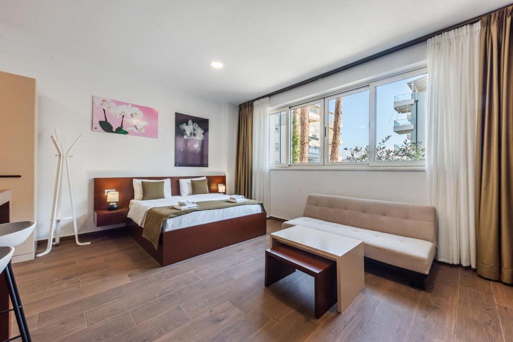 a bedroom with a bed and a couch and a window at Apart Hotel Perla Resort Lalez Durres by PikHost in Draç