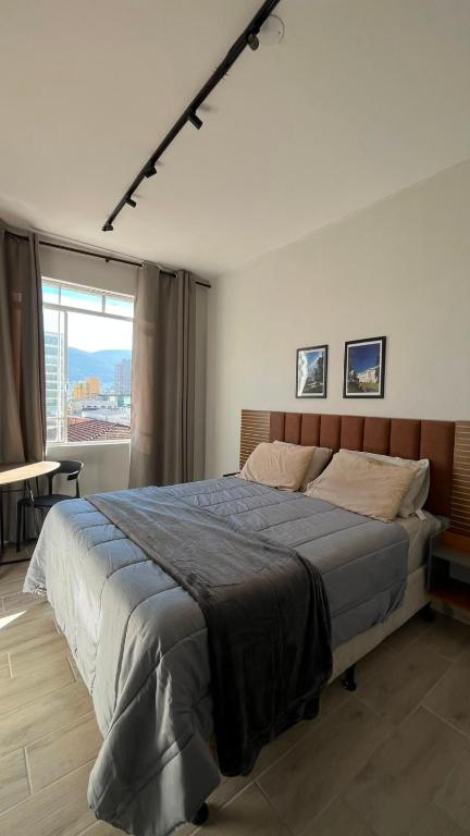 a bedroom with a large bed and a large window at Studio no Centro com VISTA PARA O CRISTO in Poços de Caldas