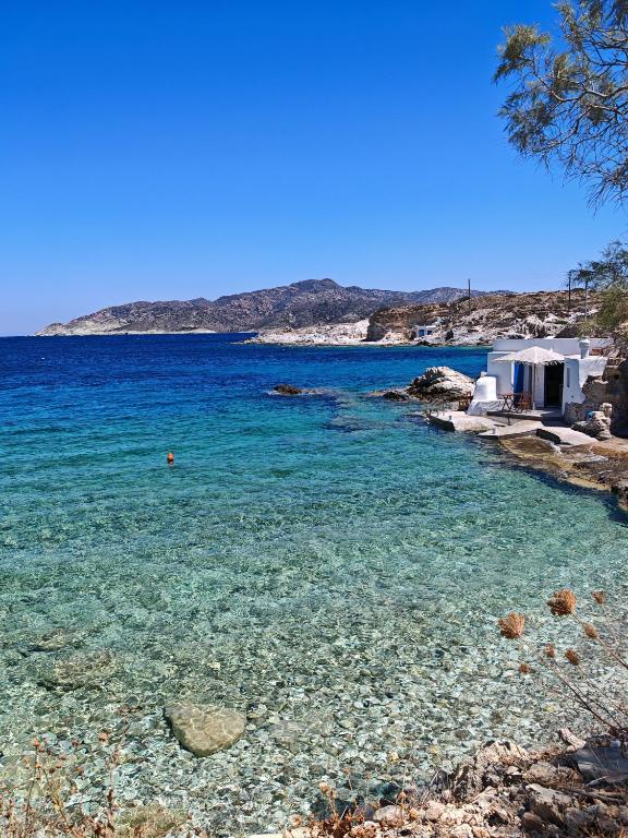 a beach with clear blue water and a house at Troulou beach house in Kimolos