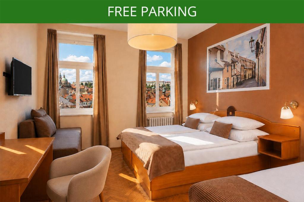 a hotel room with a bed and a desk and two windows at Hotel Merkur - Czech Leading Hotels in Prague