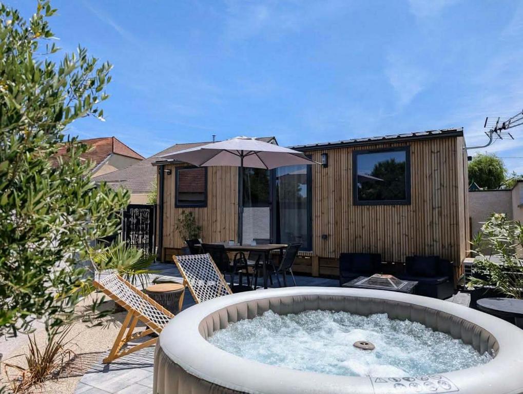 a hot tub in a patio with a table and chairs at Tiny house climatisé et jacuzzi privatif in Saint-Loup-Nantouard