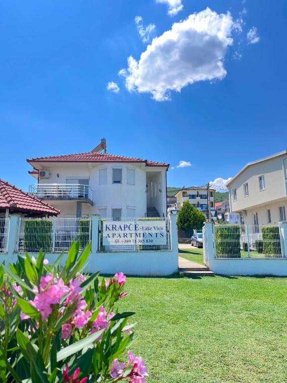 a white house with a fence and pink flowers at Krapce - Lake View Apartments in Star Dojran