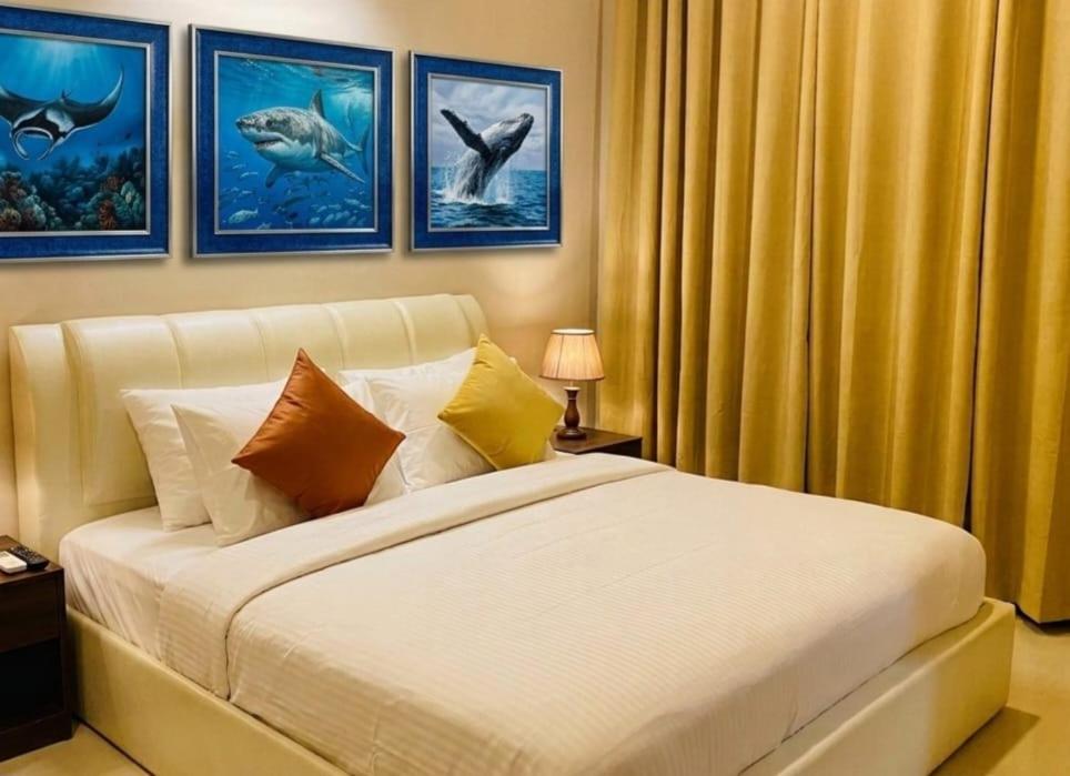 a bedroom with a bed and some pictures of dolphins at Ocean Stay & Dive in Fenfushi