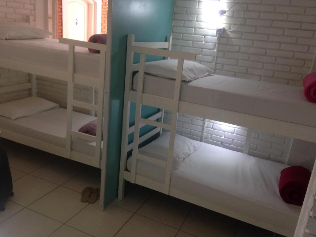 a room with three bunk beds with white shelves at Black Hotel in Bauru