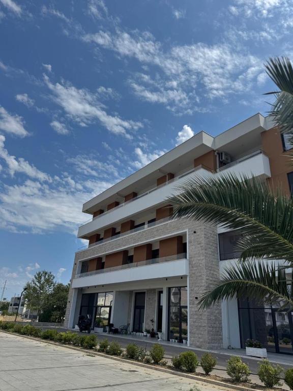 a building with a palm tree in front of it at Morea Residence in Ulcinj