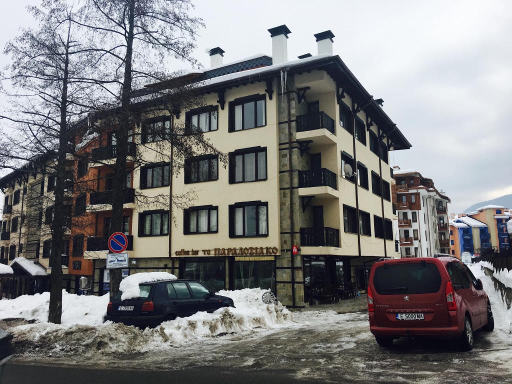a large building with cars parked in the snow at Ramada 2 Ski Apartment in Bansko