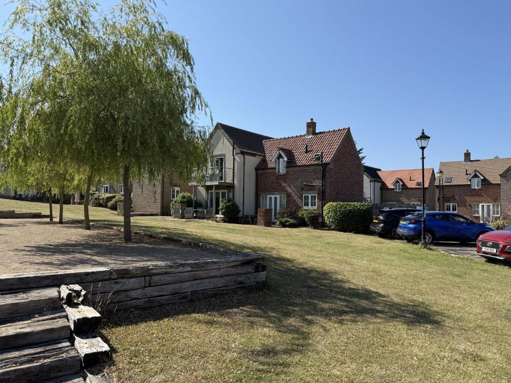 a yard with a tree and a house with cars at Anchor Down, The Bay, 2 bedrooms, patio, free parking, 2 small or 1 medium dog welcome in Filey