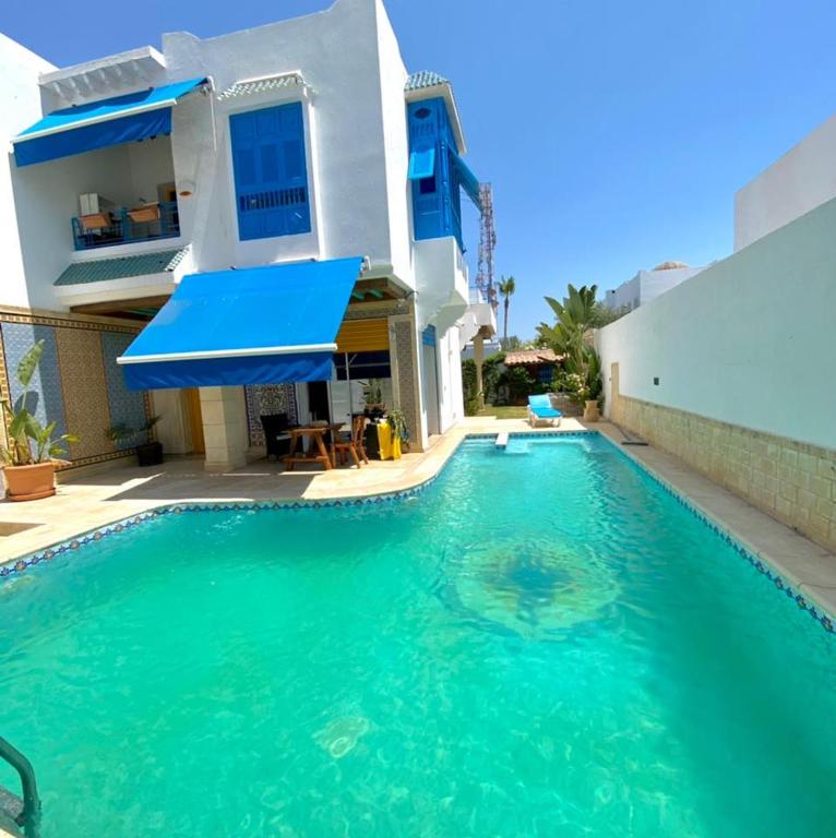 a villa with a swimming pool in front of a house at Villa Omi Zina in Nabeul