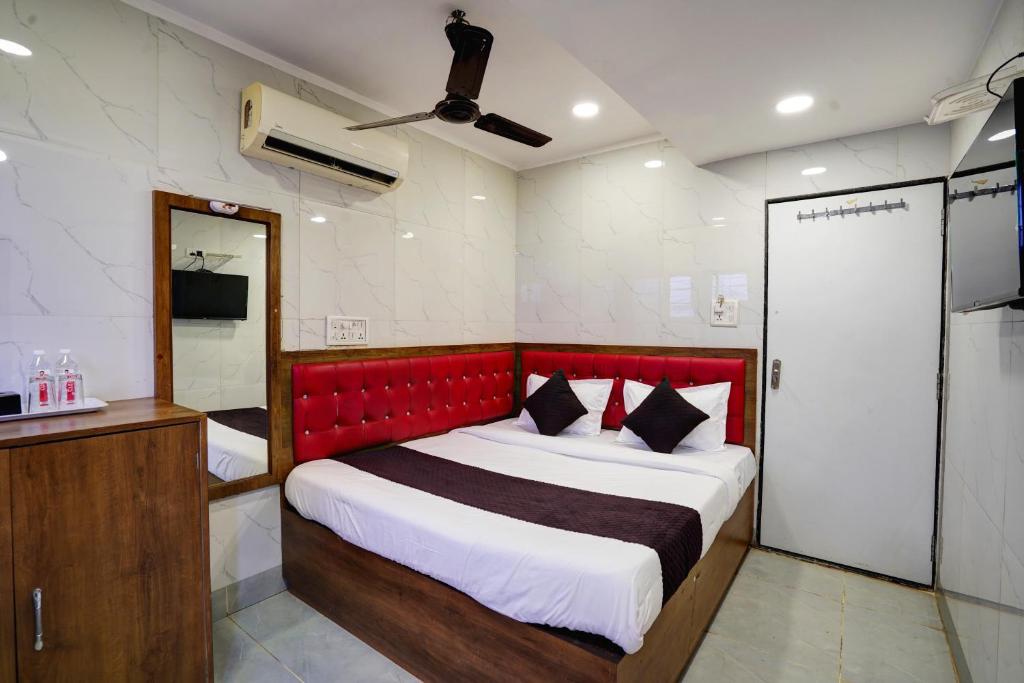 a bedroom with a large bed with a red headboard at Hotel Benz Inn in Mumbai