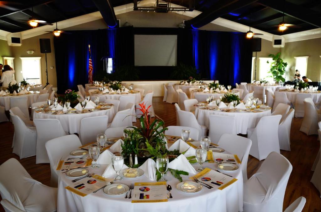 une salle de banquet avec des tables blanches et des chaises blanches dans l'établissement Grand Magnolia Ballroom & Suites, à Pascagoula