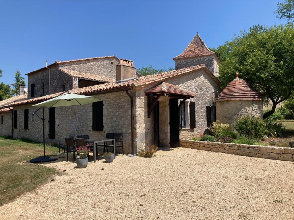 a stone house with an umbrella in front of it at Gite de Claire Fontaine avec vue sur Monflanquin in Monflanquin