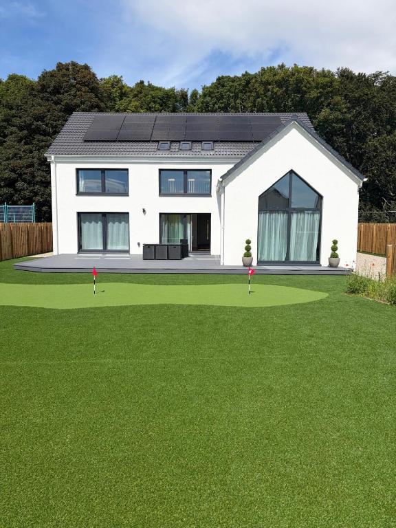 a white house with a yard with green grass at Chameleon House in Dornoch