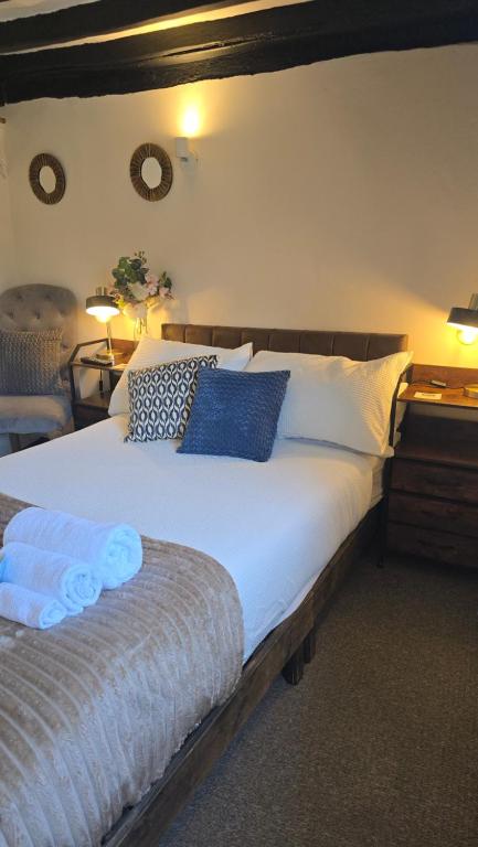a bedroom with a large bed with blue pillows at Ye Olde Red Horse in Evesham