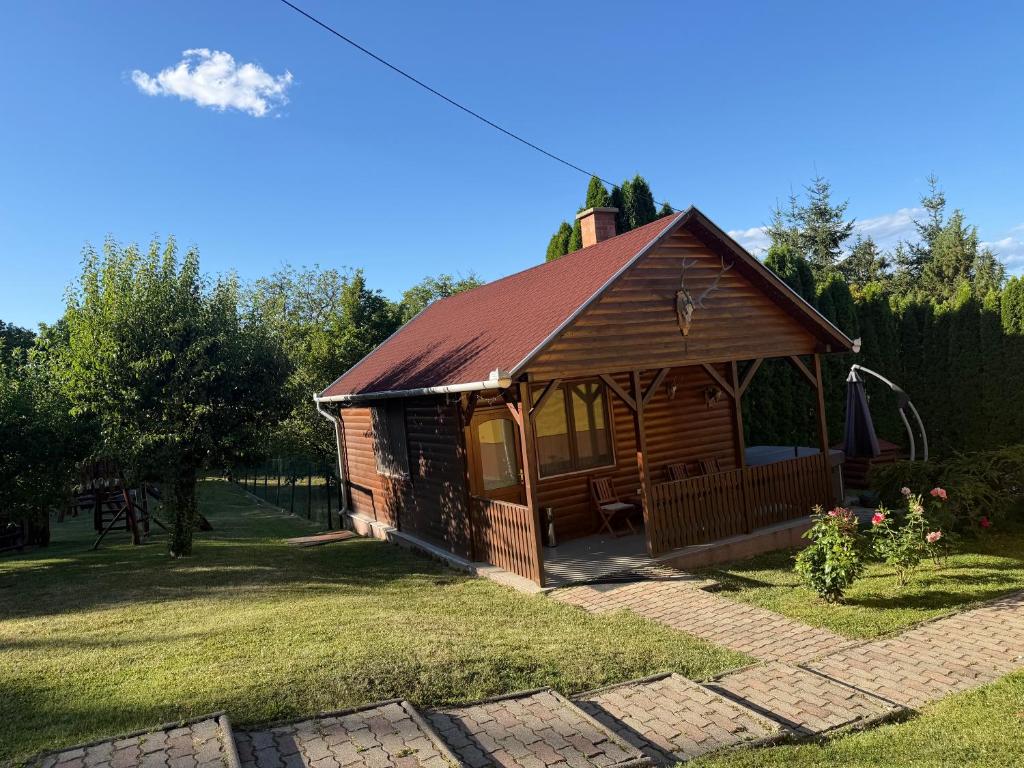 a cabin with a red roof in a yard at Flóra Apartmanok in Parádsasvár