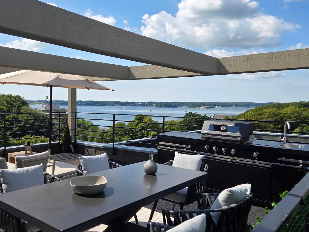 a patio with a grill and a table and chairs at Förde Loge - Traumblick & Spa in Glücksburg