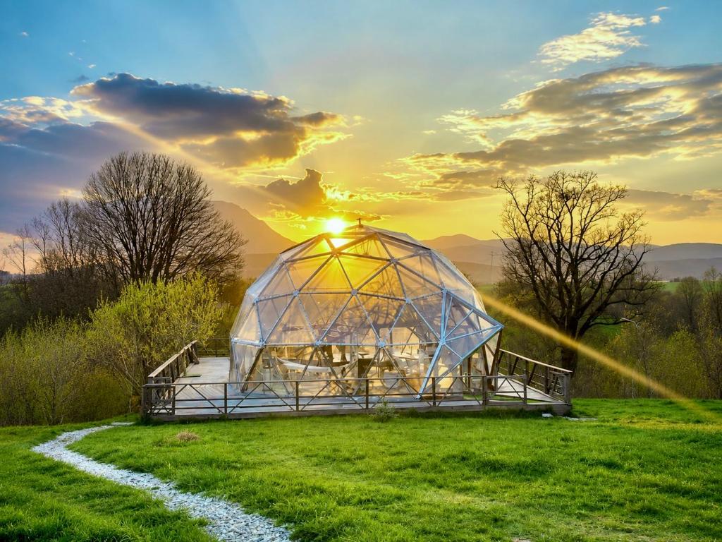 a greenhouse in a field with the sunset in the background at Soho-place in Bran