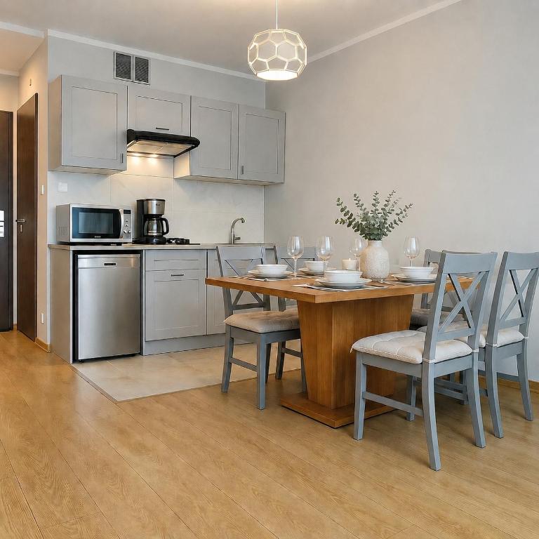 a kitchen with a wooden table and chairs and a kitchen with at Apartament Fabryczna Premium TK in Namysłów
