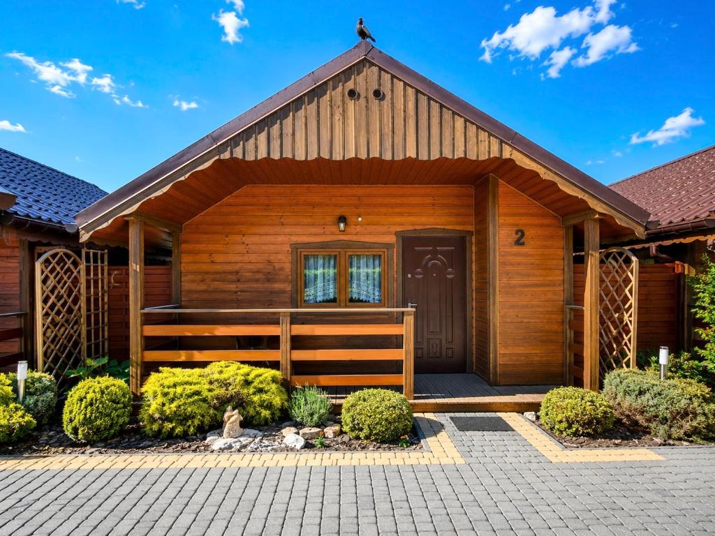 a home with a wooden house with a porch at Domki i Pokoje u Asi in Stegna