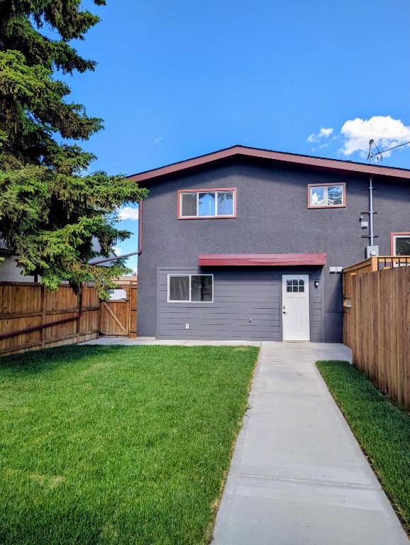 a gray house with a fence and a driveway at Mountview Maison in Red Deer