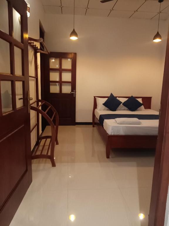 a bedroom with a bed and a chair and a door at MAYU Homestay in Dickwella