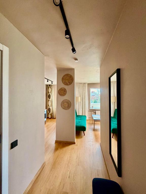 a living room with a green couch and a mirror at Freshly Renovated Black & Sand Studio in Liepāja