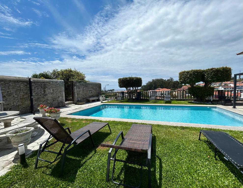 a swimming pool with two chairs and a table at Casa do Adro in Viana do Castelo