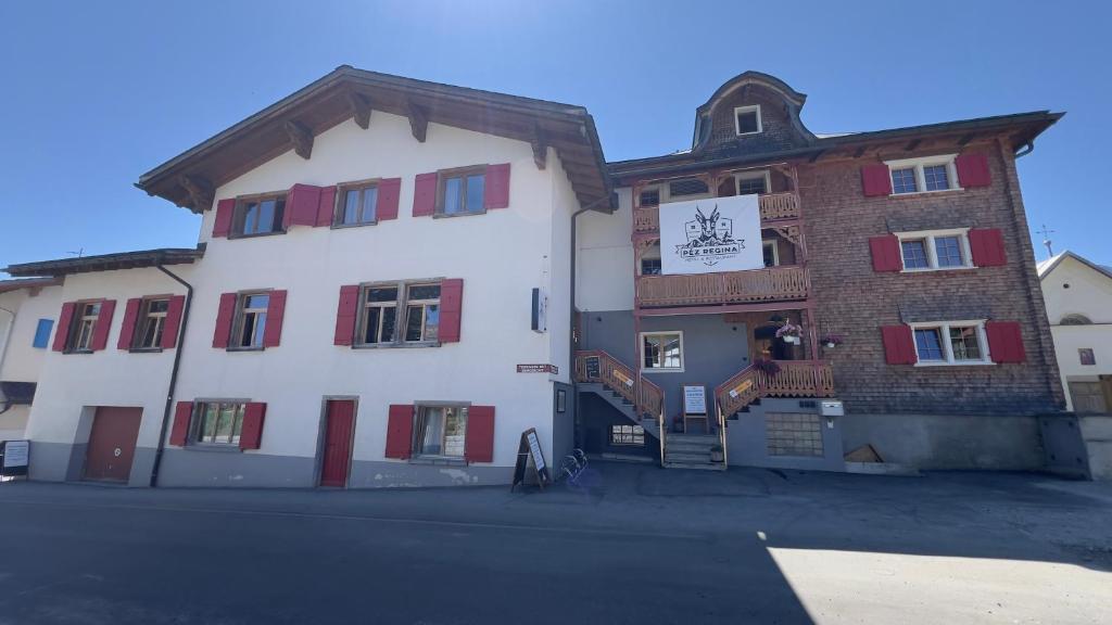 a large white building with red shuttered windows at Hotel Péz Regina in Lumbrein