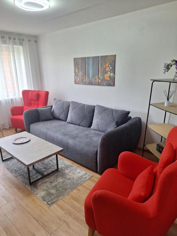 a living room with a couch and two red chairs at Spacious & sunny apartment with a balcony in Tartu