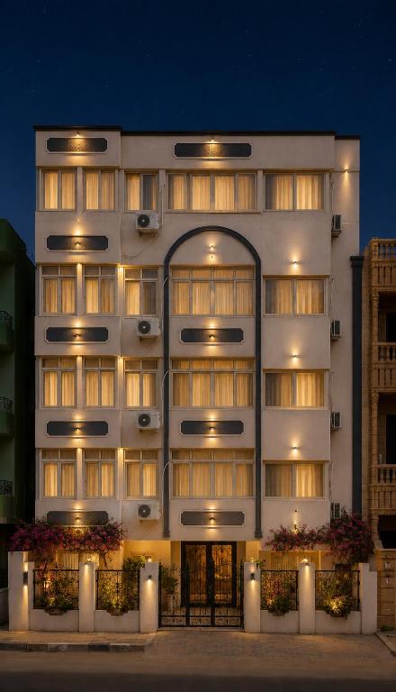 a large white building with lights on it at Hana Grand Hotel in Madinat Al Ashir min Ramadan