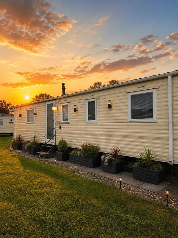 a mobile home with a sunset in the background at Carlys Cosy Caravan in Cresswell