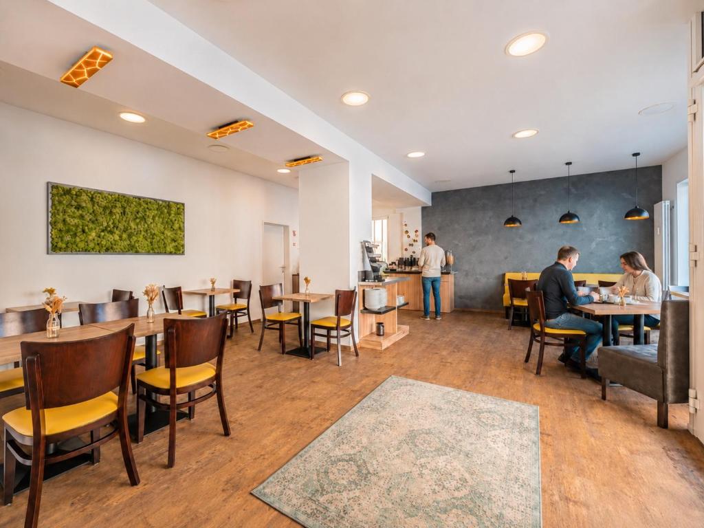 a restaurant with people sitting at tables and chairs at Hotel Gute Hoffnung Pforzheim in Pforzheim