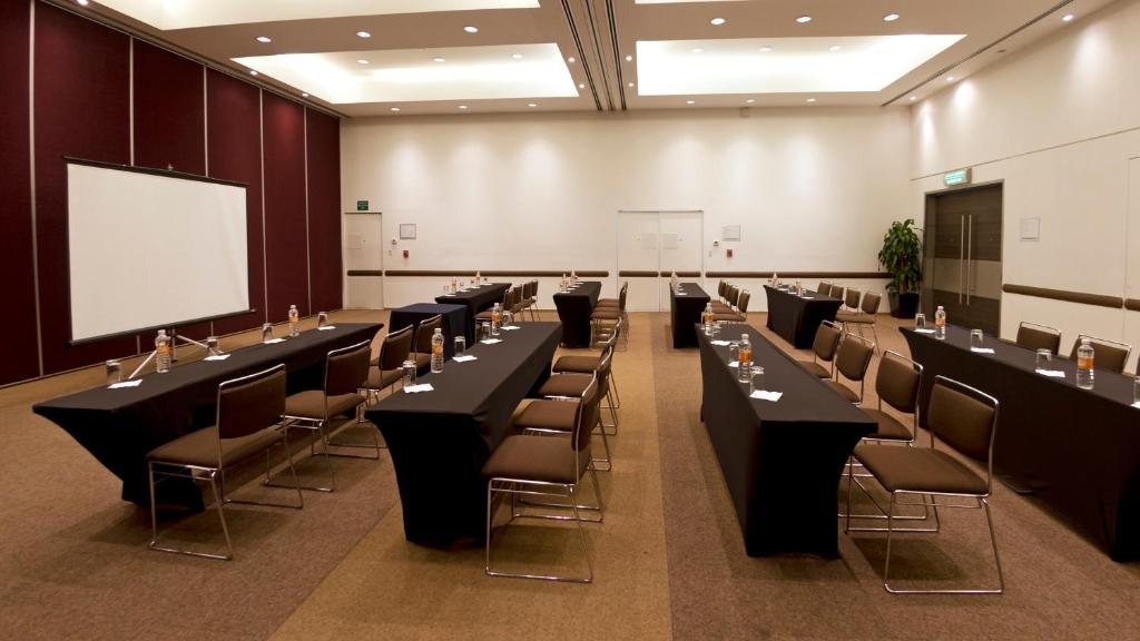 A formal conference room set with two long table blocks, chairs, water, and presentation boards.