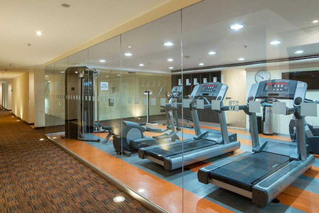The fitness room has treadmills and additional cardio and strength equipment behind glass.