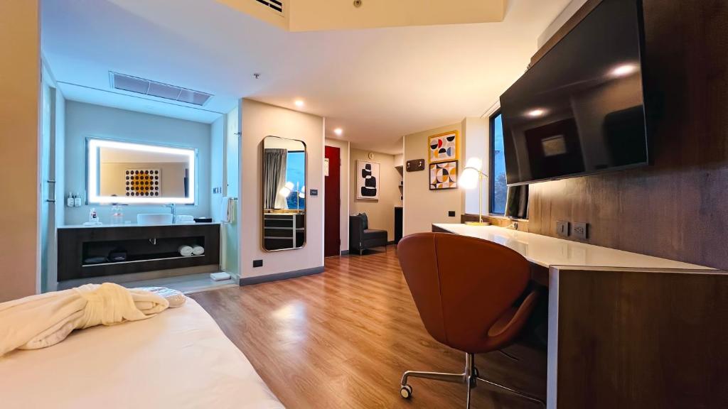 A spacious room view showing the bed, vanity, desk, minibar and television wall.