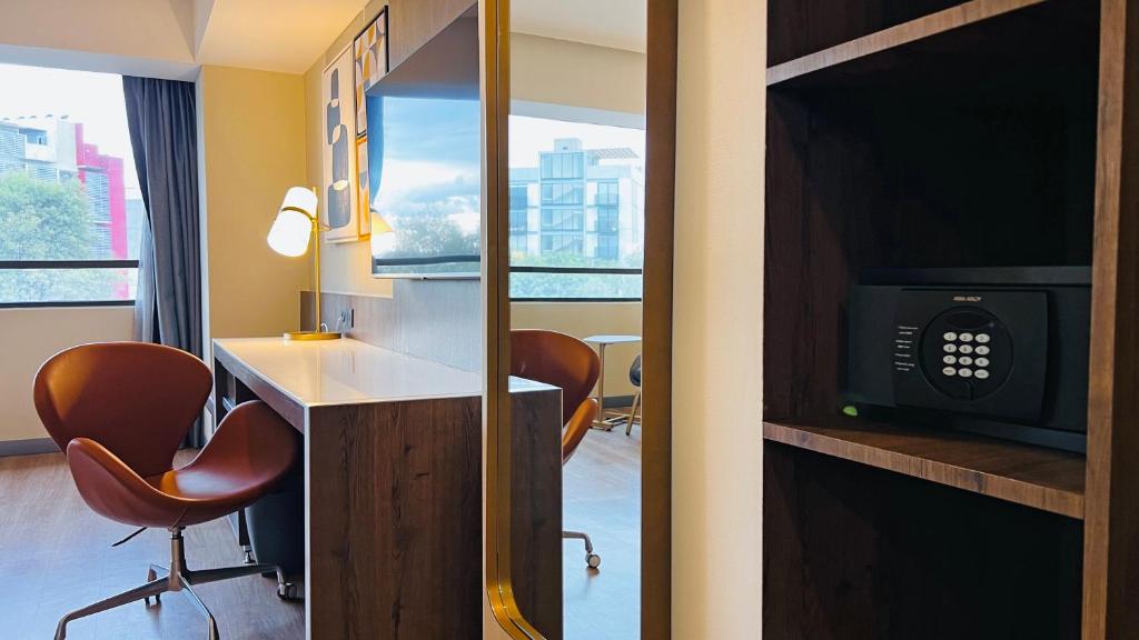 A compact in-room work area beside a window, with a safe visible in the shelving.