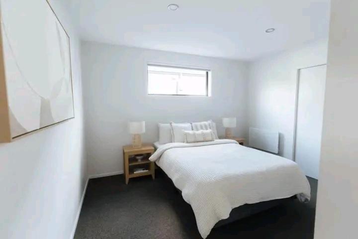 ein weißes Schlafzimmer mit einem Bett und einem Fenster in der Unterkunft Havencate in Nakuru