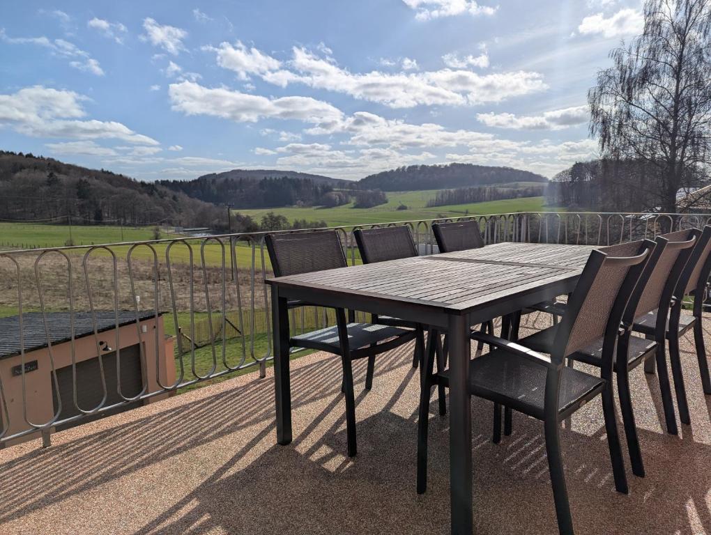 Ein Holztisch und Stühle auf einem Balkon mit Aussicht in der Unterkunft Kornkammer - Ferienhaus NaheZeit Bostalsee in Nohfelden