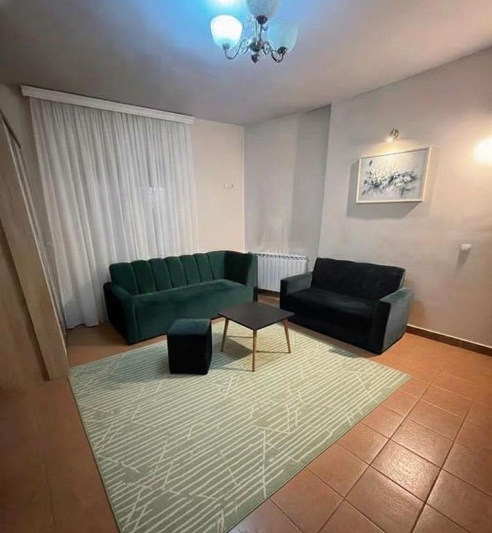 a living room with a green couch and a table at Kosvegas Apartment in Kosovo Polje