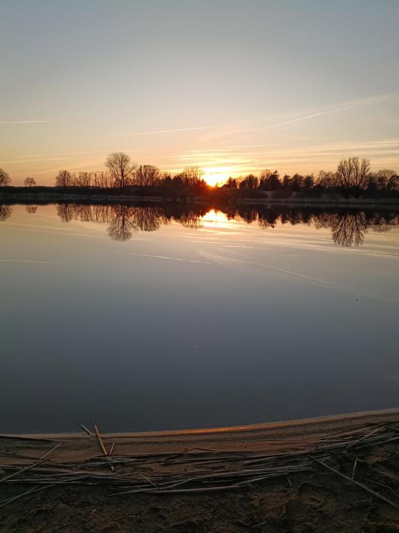 a view of a lake at sunset at Ferien am Schloss - Wohnung 4 "der Hund", Ferienwohnung am Badesee in Behren-Lübchin