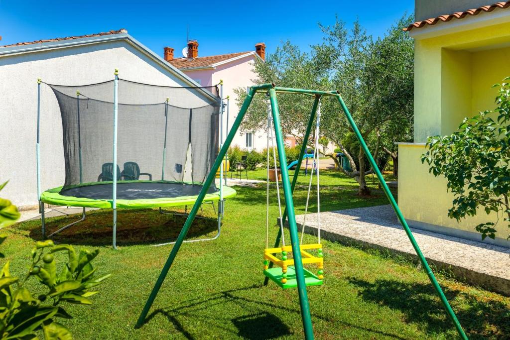 a playground with a trampoline in a yard at Apartmani Prodan 2 in Fažana