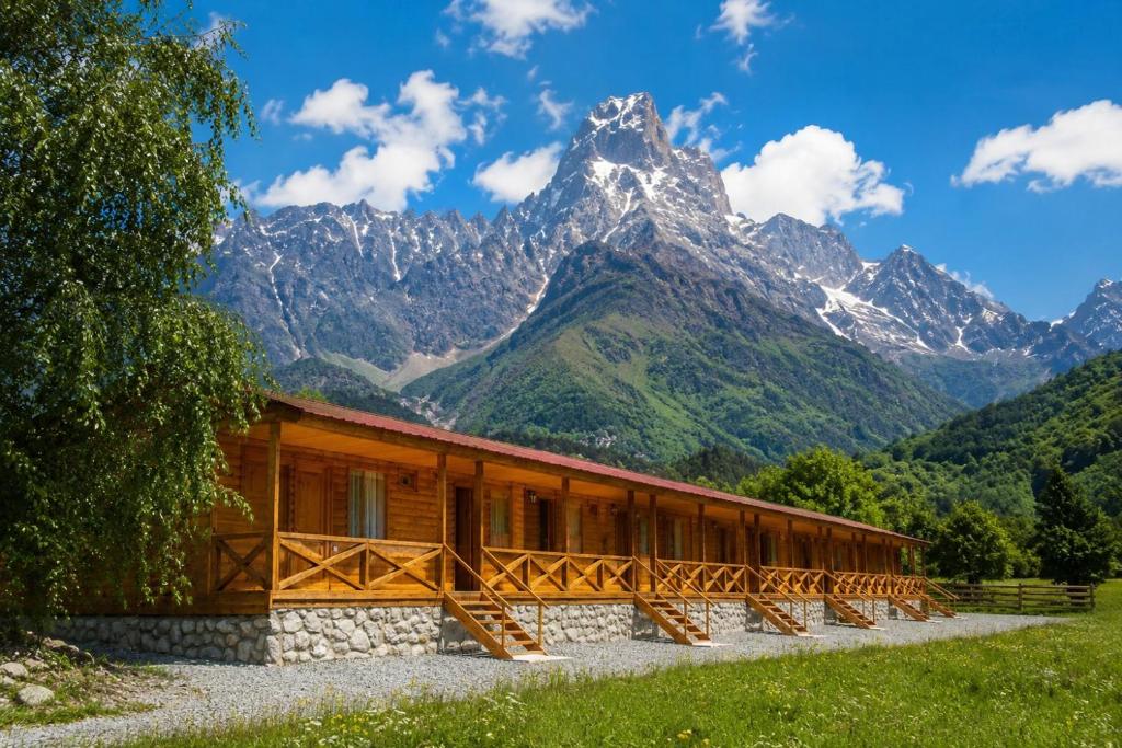 a wooden building with a mountain in the background at Ushba Hill Panoramic Lodge Becho in Mestia