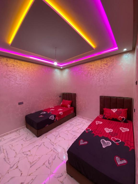 two beds in a room with purple lights at Tamri beach house in Agadir
