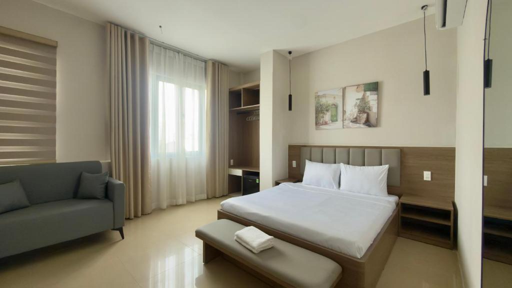 a bedroom with a bed and a chair and a couch at Ann Arbor Hotel in Ho Chi Minh City