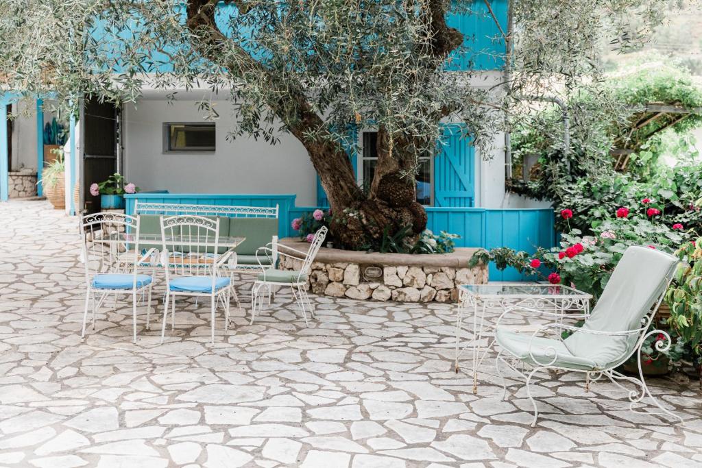 a patio with chairs and a tree in front of a building at Afroditi Pansion in Agios Nikitas