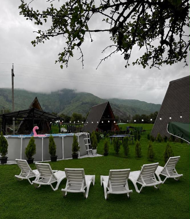 a group of white chairs sitting on the grass at Hillside Borjomi Two chalet in Borjomi