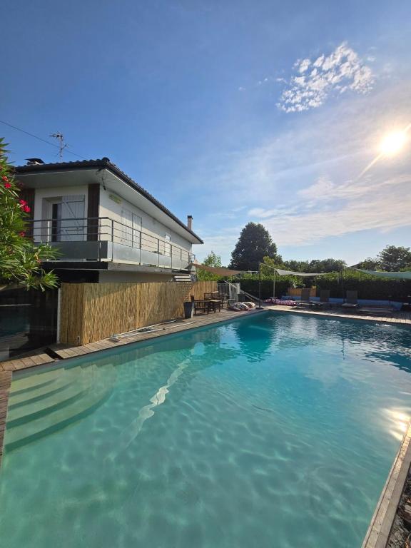 a swimming pool with blue water in front of a house at La Villa Belle in Biscarrosse