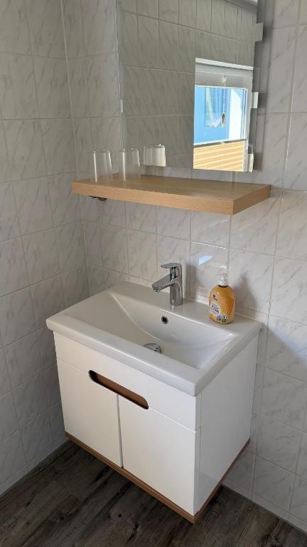 a bathroom with a white sink and a shelf at Ferienwohnung in Zirchow