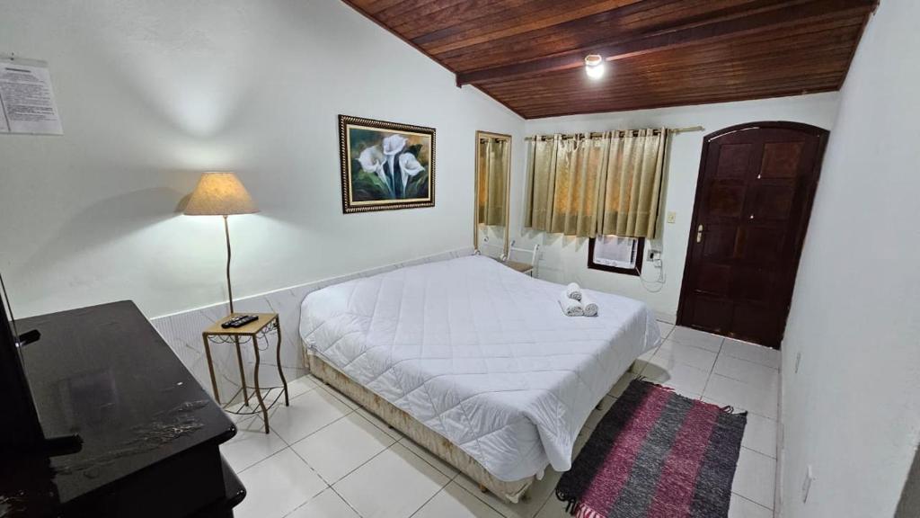 a bedroom with a bed and a table and a lamp at Pousada das Acerolas in Penedo