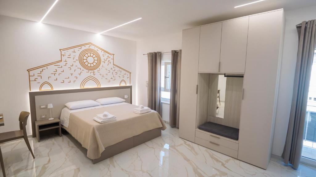 a white bedroom with a bed and a tv at VIBINUM Bed & Breakfast in Bovino