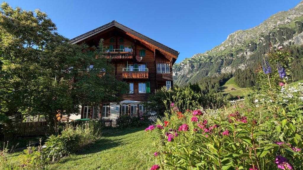 a house in the mountains with flowers in the foreground at Staubbachbänkli in Wengen